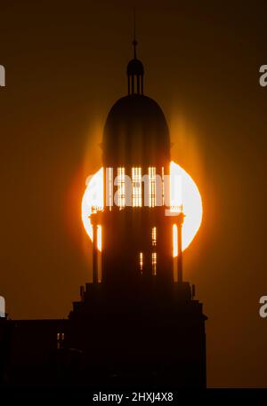 Berlino, Germania. 13th Mar 2022. Il sole sorge dietro una torre della porta di Francoforte. Credit: Annibal Hanschke/dpa/Alamy Live News Foto Stock