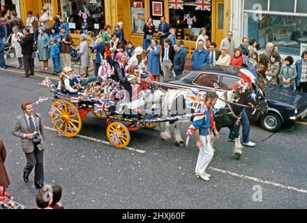 Una sfilata del 6 giugno 1977 per celebrare il Giubileo d'Argento della Regina Elisabetta II Ciò si è svolto a Sheen Lane, East Sheen, nel SW14 di Londra, Inghilterra, Regno Unito. Qui un cavallo e un carretto a tema zingaro passa lungo la strada. Le bandiere di Union Jack di tutte le dimensioni sono in mostra. Il venticinquesimo anniversario dell’incoronazione della Regina è stato il 6 febbraio 1977, ma il 7 giugno è stato designato per una grande giornata ufficiale e non ufficiale in tutto il paese. Questa immagine proviene da una vecchia trasparenza del colore amatoriale – una fotografia d'epoca del 1970s. Foto Stock