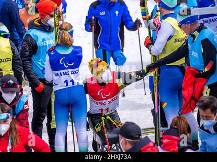 Zhangjiakou, Cina. 13th Mar 2022. Paralimpiadi, Para Ski Nordic, Cross Country, Freestyle, Open Relay, Martin Fleig (classificazione Paralimpica, LW 11,5 seduta) della Germania si siede tra i suoi compagni tedeschi al traguardo dopo la gara Open Relay di 4 x 2,5 chilometri. Fleig sta terminando la sua carriera di para-biatleta e sciatore di fondo. Il portatore tedesco di bandiera ha fatto l'annuncio alla cerimonia di apertura in Cina alla sua terza Paralimpiadi generale. Credit: Jens Büttner/dpa-Zentralbild/dpa/Alamy Live News Foto Stock