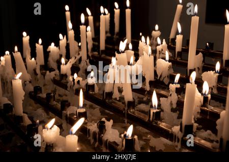 Candele votive o candele di preghiera rack illuminato in una chiesa, tradizione cristiana. Foto Stock