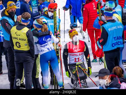 Zhangjiakou, Cina. 13th Mar 2022. Paralimpiadi, Para Ski Nordic, Cross Country, Freestyle, Open Relay, Martin Fleig (classificazione Paralimpica, LW 11,5 seduta) della Germania si siede tra i suoi compagni tedeschi al traguardo dopo la gara Open Relay di 4 x 2,5 chilometri. Fleig sta terminando la sua carriera di para-biatleta e sciatore di fondo. Il portatore tedesco di bandiera ha fatto l'annuncio alla cerimonia di apertura in Cina alla sua terza Paralimpiadi generale. Credit: Jens Büttner/dpa-Zentralbild/dpa/Alamy Live News Foto Stock