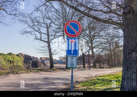 Segnaletica stradale: Senza parcheggio, questa strada è un punto morto e percorso ciclabile, tavole rotonde e rettangolari in blu, rosso, bianco e verde, strada rurale con alberi Foto Stock