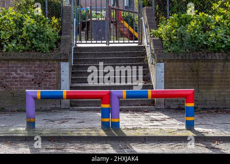 Protezione posti sul marciapiede all'ingresso di una scuola con scale in mattoni, cancello di metallo e il parco giochi in sfondo sfocato, viola, rosso, Foto Stock