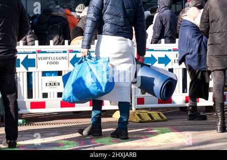 Amburgo, Germania. 13th Mar 2022. I rifugiati ucraini attendono di fronte all'Ufficio per le migrazioni presso il punto di registrazione dei rifugiati a Hammer Straße. Un uomo porta una borsa Ikea e un tappeto. Credit: Daniel Bockwoldt/dpa/Alamy Live News Foto Stock