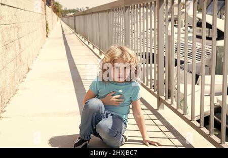 Pausa respiro. Ragazzo relax hunkering giù sul lungomare. Bambino ragazzo prendere riposo breve Foto Stock