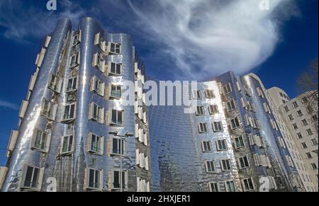 Dusseldorf (Medienhafen), Germania - Marzo 1. 2021: Vista sulla casa Gehry con facciata in alluminio metallizzato lucido argento futuristico contro il cielo blu profondo Foto Stock