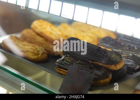 Varietà di torte di crema al forno in vetrata presso il forno caffetteria. I pasticcini caldi si trovano sullo scaffale del caffè. Foto Stock