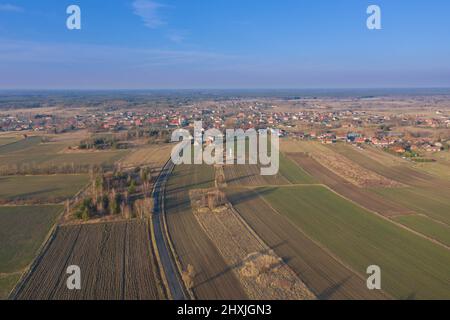 Una vasta pianura, campi arabili e prati tra i quali si può vedere una strada asfaltata grigia. È una giornata di sole, le auto sono alla guida su strada. Foto dal drone Foto Stock