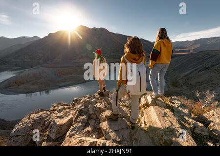 Gruppo di tre escursionisti femminili con zaini al punto di vista del tramonto Foto Stock