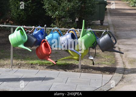 12 marzo 2022, Renania Settentrionale-Vestfalia, Colonia: Le lattine di plastica colorate appendono su uno stand al cimitero di Melaten e possono essere prese in prestito. Foto: Horst Galuschka/dpa Foto Stock