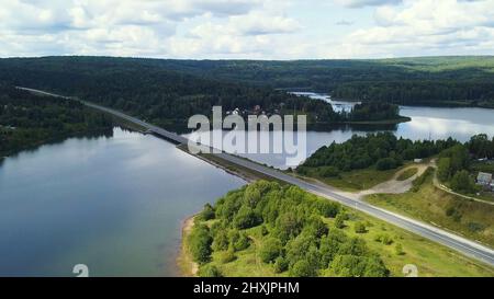 Un enorme ponte sul fiume. Clip. Vista dall'alto. Un enorme ponte su un grande fiume sullo sfondo di un cielo senza nuvole e di un'enorme foresta Foto Stock