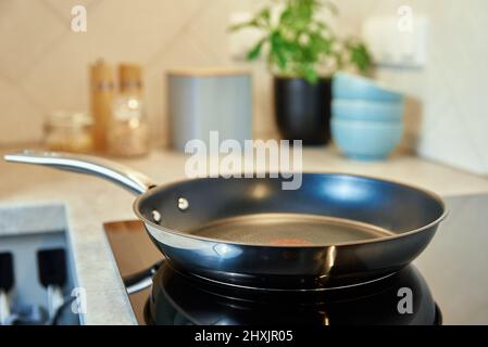 Padella in acciaio in cucina con piano cottura elettrico a induzione, moderno apparecchio da cucina Foto Stock