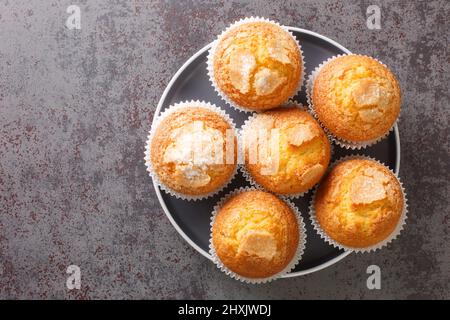 Primo piano di un mucchio di magdalenas i tipici muffin spagnoli pianura nel piatto sul tavolo. Vista dall'alto orizzontale Foto Stock