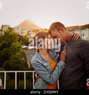 Avvolto nell'amore. Scatto di una giovane coppia felice godendo un momento romantico in città. Foto Stock