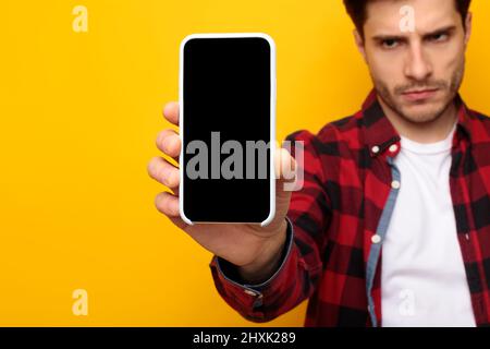 Un ragazzo triste che tiene in mano lo schermo dello smartphone vuoto Foto Stock