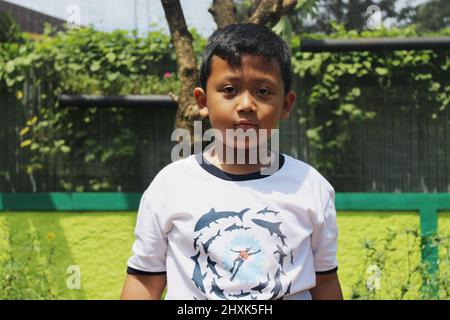 Jakarta, Indonesia - 12 24 2020: Ragazzo che si alza alto e guarda la macchina fotografica mentre in vacanza nel Taman Mini Indonesia Indah giardino, Jakarta Foto Stock