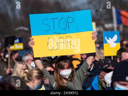 Amburgo, Germania. 13th Mar 2022. Un partecipante a una manifestazione contro il conflitto ucraino si trova sul Jungfernstieg e sostiene una lettura di cartello "Stop the war”. Credit: Daniel Bockwoldt/dpa/Alamy Live News Foto Stock