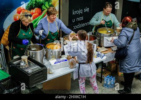 Le donne polacche danno zuppa calda ai rifugiati ucraini, poiché molti individui polacchi forniscono volontariamente aiuto ai rifugiati colpiti dalla guerra nella stazione ferroviaria principale di Cracovia, mentre più di 1,5 milioni di persone sono già fuggite dall'Ucraina per la Polonia. Mentre la Federazione russa ha invaso l'Ucraina, il conflitto dovrebbe costringere fino a 5 milioni di ucraini a fuggire dal paese. Molti dei rifugiati chiederanno asilo in Polonia. La maggior parte degli aiuti di beneficenza in Polonia è fornita da individui, ONG e imprese. Le persone in fuga sono spesso accolte da individui e ONG. Foto Stock