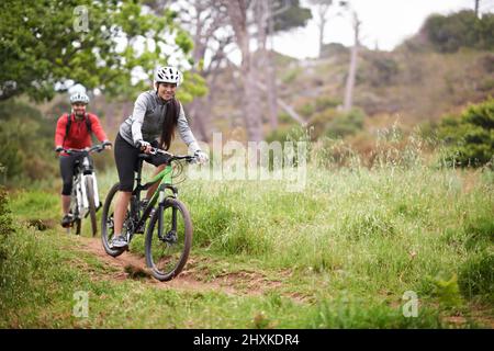 Esplorare le strade meno viaggiate. Un paio di giovani ciclisti che si divertono all'aria aperta e si tengono in forma in mountain bike. Foto Stock