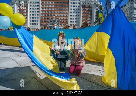 I manifestanti si presentano con bandiere ucraine durante un raduno contro l'invasione russa dell'Ucraina a Plaza de España. Foto Stock