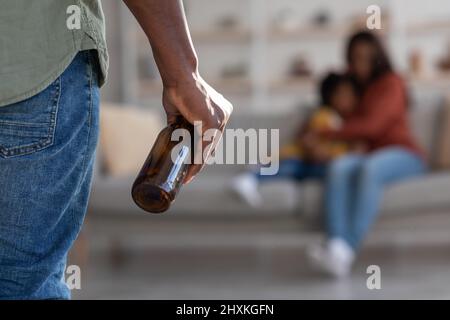 Black Man Holding bottiglia di alcol e minaccia moglie e piccola figlia Foto Stock