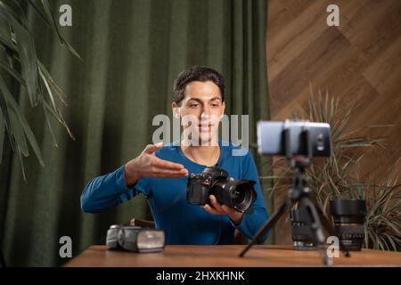 il fotografo di arab Guy fornisce una panoramica delle impostazioni della fotocamera e registra un tutorial video utilizzando uno smartphone su un cavalletto. Tirocinio fotografico online Foto Stock