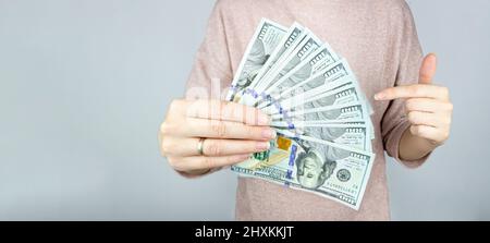 Un sacco di valuta americana in una mano femminile. Mano che tiene fuori un pacchetto di dollari fanned Foto Stock