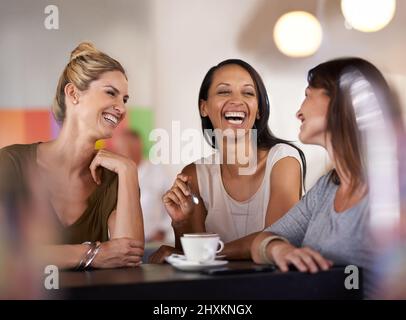 Lei sa come far sorridere tutti. Scatto di tre donne che si godono una conversazione in un ristorante. Foto Stock