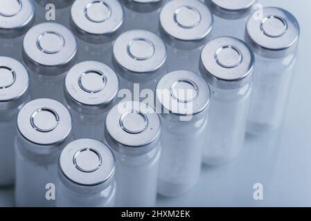 Flaconcino di fiala medica di vetro per iniezione. La medicina è polvere bianca secca della penicillina del farmaco o liquido con di soluzione acquosa in ampolla. Primo piano. Bottiglie ampule con tappo in alluminio su sfondi grigio. Foto Stock