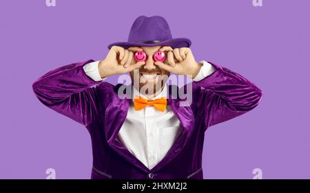 Divertente ritratto in studio di un uomo allegro che copre gli occhi con due emoticon sorridenti Foto Stock