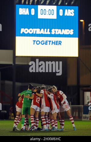 I giocatori di Arsenal in un gruppo huddle come "il calcio si leva insieme" è visualizzato sul grande schermo prima della partita della lega delle donne della Barclays fa al popolare stadio di pensione, Crawley. Data foto: Domenica 13 marzo 2022. Foto Stock