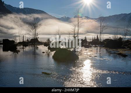 Sole pomeridiano visto da Seewiese con nebbia che si innalza dal lago e dalla montagna di Sarstein sullo sfondo Foto Stock