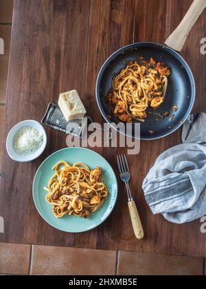 Pranzo in stile mediterraneo. Spaghetti con cozze, salsa di pesce e pomodoro, fatti in casa. Su un tavolo di legno, vista dall'alto. Ambiente piatto. Verticale. Foto Stock