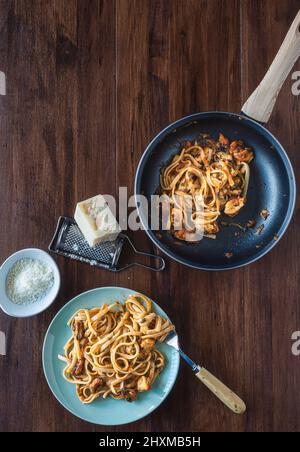 Pranzo in stile mediterraneo. Spaghetti con cozze, salsa di pesce e pomodoro, fatti in casa. Su un tavolo di legno, vista dall'alto. Ambiente piatto. Verticale. Foto Stock