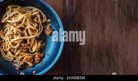 Padella di spaghetti con cozze, pesce e salsa di pomodoro appena sfornata. Fatto in casa. Su tavola di legno, vista dall'alto. Ambiente piatto. Orizzontale. Foto Stock
