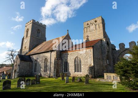 Una vista laterale posteriore sia della Chiesa che delle rovine Priorie della Chiesa di Weybourne nel Norfolk del Nord nel Regno Unito in una bella giornata di cielo blu Foto Stock