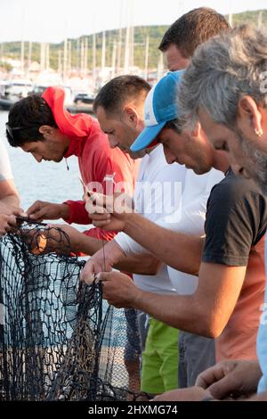 Tribunj, Croazia - 23 agosto 2021: Gruppo di pescatori che riparano la rete da pesca , primo piano Foto Stock