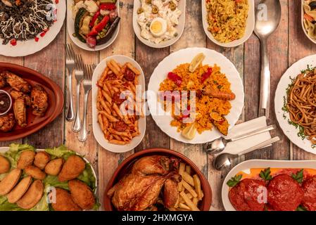 Set di piatti assortiti di maccheroni spagnoli con pomodoro e chorizo, pollo arrosto, insalata russa, paella e riso nero con calamari, gnocchi Foto Stock