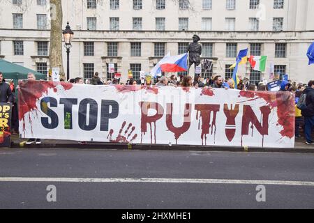 Londra, Regno Unito. 13th Mar 2022. I manifestanti hanno in mano una bandiera di 'Spop Putin' durante la manifestazione. Migliaia di manifestanti si sono riuniti fuori Downing Street a sostegno dell'Ucraina mentre la Russia continua il suo attacco. Credit: SOPA Images Limited/Alamy Live News Foto Stock