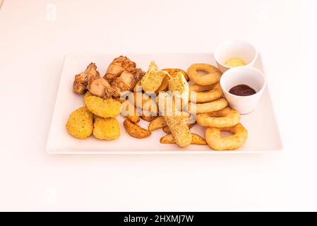 Uno degli antipasti più semplici e deliziosi che esistono sono anelli croccanti di cipolle, crocchette, strisce di formaggio, noccioline e salse assortite. Foto Stock