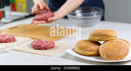 Mano della donna che forma una carne di manzo per una festa di hamburger. Porzionamento carne macinata. Hamburger fatti in casa. Fare il cibo a casa. Foto Stock