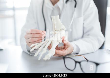 Medico che spiega l'operazione al piede sul modello osseo Foto Stock