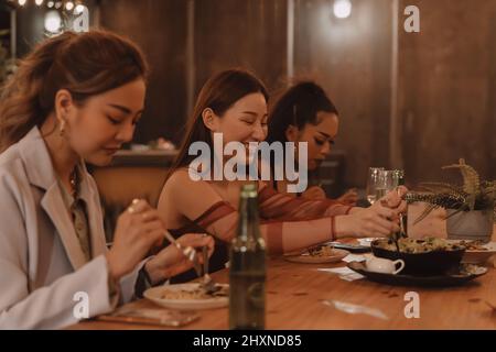 I giovani amici asiatici mangiano e gustano la cena insieme al ristorante all'aperto. Celebrazione dell'amicizia e della riunione Foto Stock