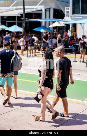 Miami Beach, FL, USA - 12 marzo 2022: Coppia con molti tatuaggi che camminano lungo Ocean Drive Spring Break Foto Stock