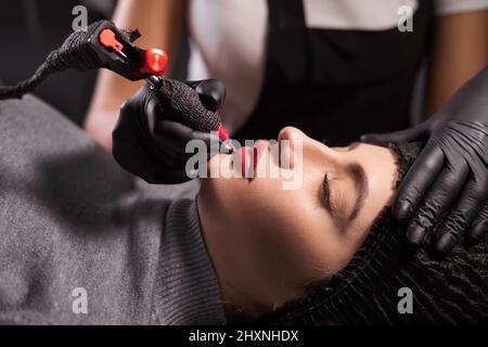 Ritratto del maestro durante l'applicazione di trucco permanente sulle labbra. Tatuaggio sul viso e micropigmentazione delle labbra. Professionale Foto Stock