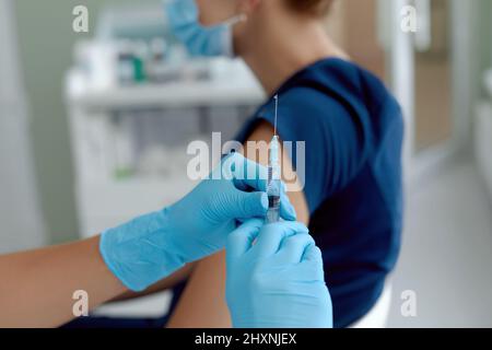 primo piano medico di tenuta siringa fare l'iniezione al paziente in maschera medica. Covid-19 o vaccino contro il coronavirus Foto Stock