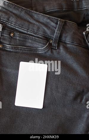 La parte superiore di vecchi jeans neri indossati con tasche e un tag bianco per i vestiti Foto Stock