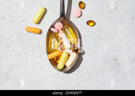 Diversi tipi di compresse, pillole, capsule e vitamine in un cucchiaio. Dose giornaliera di integratori per la salute. Foto Stock