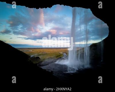 All'interno della cascata Seljalandsfoss all'alba in Islanda Foto Stock
