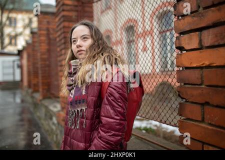 Giovane studentessa con sindrome di Down che cammina per strada in inverno Foto Stock